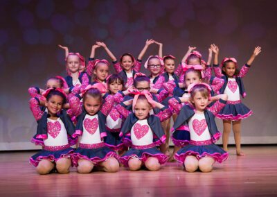 A group of young children wearing pink and blue outfits, standing together.