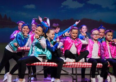 A vibrant ensemble of children wearing colorful outfits performing on stage.