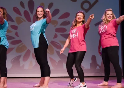 A group of people dancing with vibarnt dress color